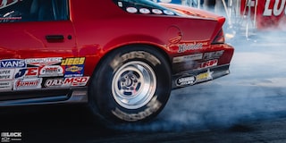 Rear Side View of a Red Chevrolet Sports Car Burning Rubber at the 2024 NHRA 4-Wide Nationals