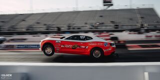 Side View of a Red Chevrolet Funny Car Racing With the Two Front Wheels Lifted off the Track at the 2024 NHRA 4-Wide Nationals