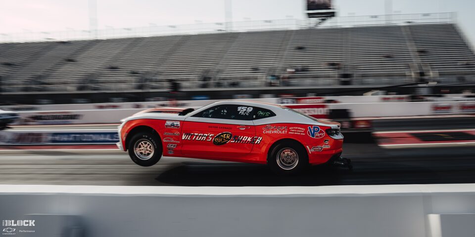 Side View of a Red Chevrolet Funny Car Racing With the Two Front Wheels Lifted off the Track at the 2024 NHRA 4-Wide Nationals