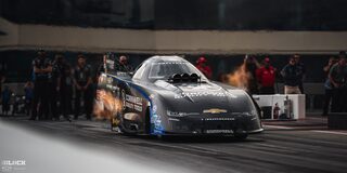 Front View of a Black Chevrolet Camaro Funny Car Spitting Flames as It Speeds Down the Track at the 2024 NHRA 4-Wide Nationals