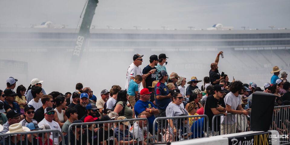 An Excited Crowd Watches Races at the 2024 Texas C10 Nationals With Smoke Billowing in the Backgrouund