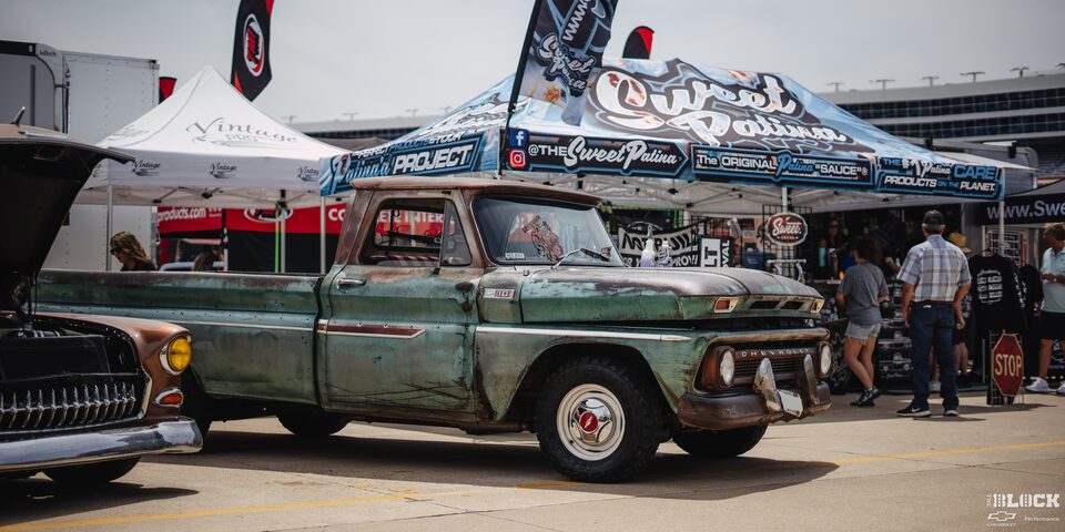 A Vintage Green Chevy Pickup Truck Parked Next to a "Sweet Patina" Tent at Texas Motor Speedway
