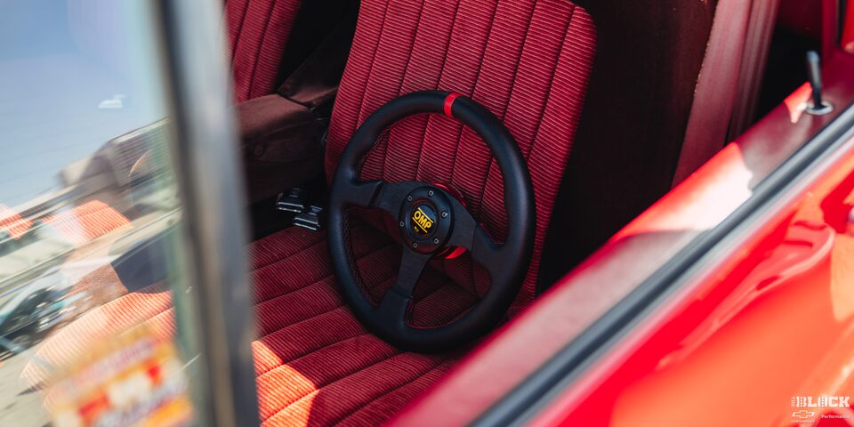 An OMP Steering Wheel Rests on the Red Fabric Upholstery in a Classic Chevy Truck