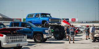 A Blue Chevy Monster Truck Towers Over Other Parked Pickups at Texas Motor Speedway