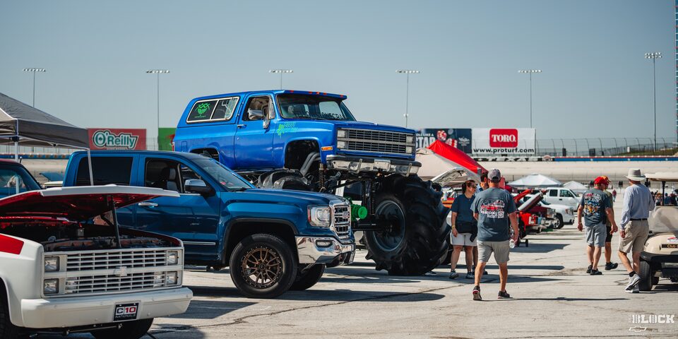 A Blue Chevy Monster Truck Towers Over Other Parked Pickups at Texas Motor Speedway