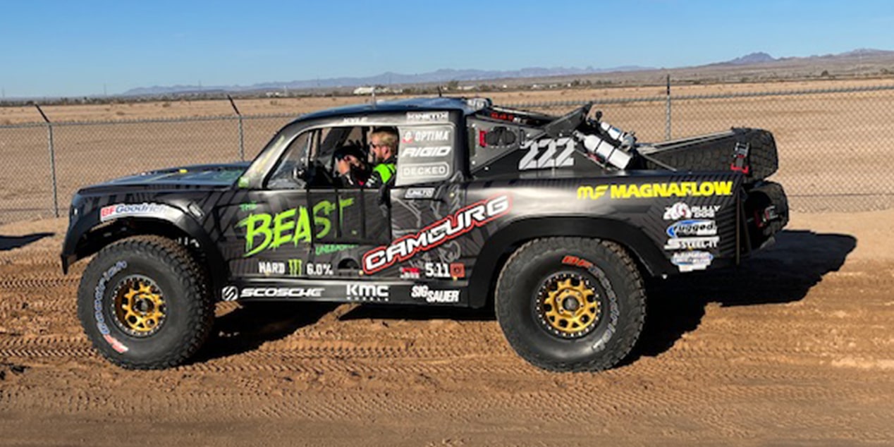 Side View of a Custom Black Colored Vehicle with a Man on the Driver's Seat in the Desert