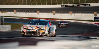 Three Quarters View of a Custom Chevy Racecar Driving Down the Track with Sunlight Hitting Its Front