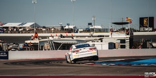 Rear View of a White Custom Chevy Racecar Swayed to the Left with the Right Side Slightly Lifting off the Track