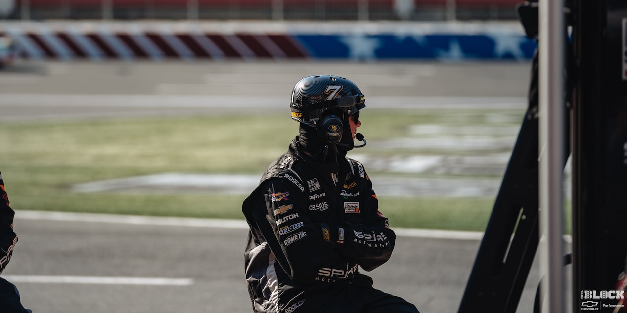 A Racer Is Seen Sitting Down with a Black Outfit on While Looking In the Distance