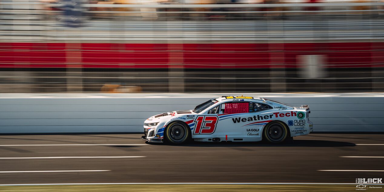 Side View of a White Custom Racecar Speeding Down the Track