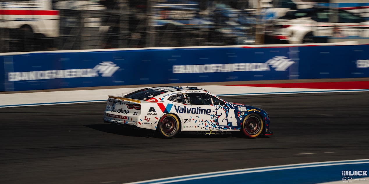 Three Quarters Rear View of a White Chevy Racecar Driving Down the Track in the Afternoon