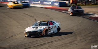 Three Quarters View of Many Racecars Driving Down the Racetrack on a Sunny Day