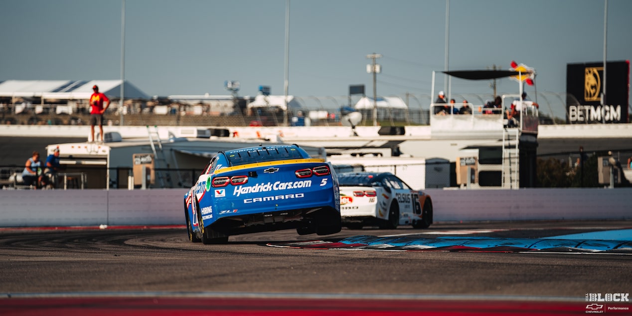 Rear View of a Blue Custom Chevy Racecar Swayed to the Left with the Right Side Slightly Lifting off the Track
