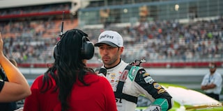 A Racer Wearing White Cap and Outfit Listening to Racing Staff