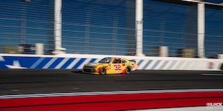 Three Quarters View of a Yellow Chevy Racecar on the Track on a Sunny Day