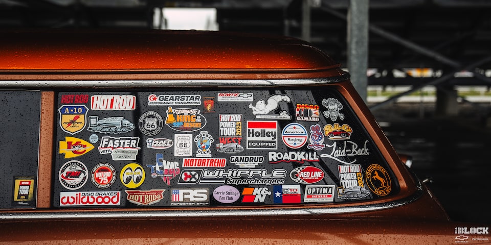 Side View of Many Company Logos on the Left Rear Window of a 1955 Orange Chevy Handyman Wagon