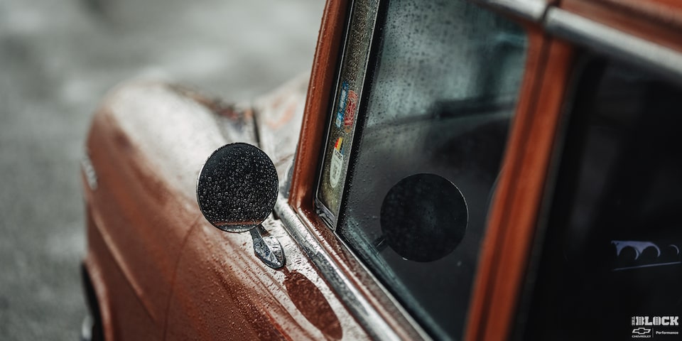 A Shot of a Side View Mirror of a 1955 Chevy Handyman Wagon Covered in Water Droplets from Rain