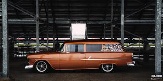 Side View of an Orange Chevy 1955 Handyman Wagon Wet from the Rain Parked under the Shade