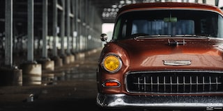 Front View of a Wet Chevy 1955 Handyman Wagon on the Left Side of the Frame under the Shade in Rainy Weather