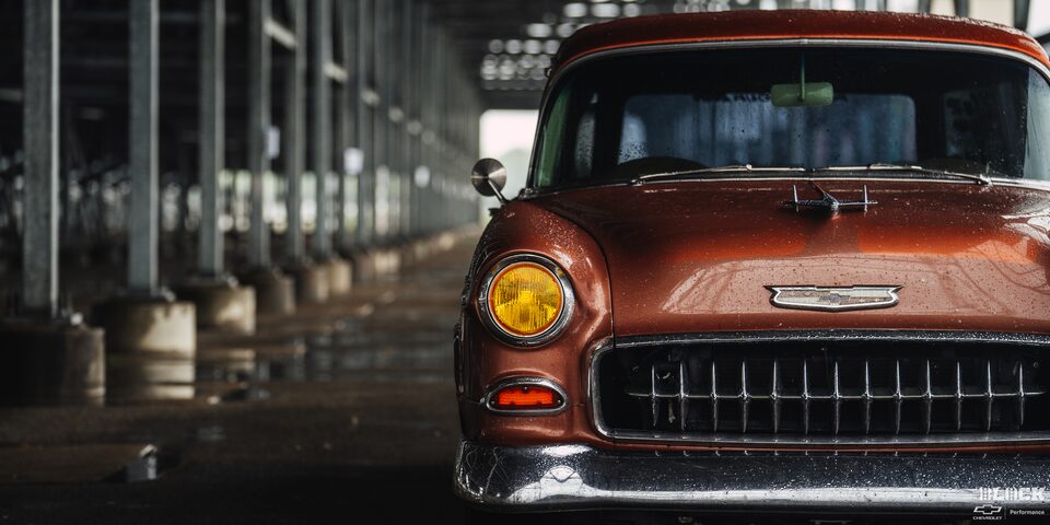 Front View of a Wet Chevy 1955 Handyman Wagon on the Left Side of the Frame under the Shade in Rainy Weather
