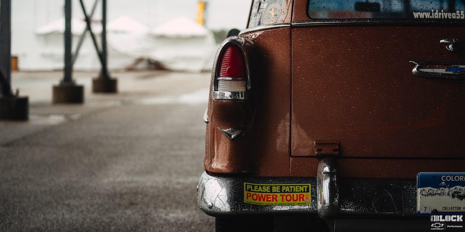 Rear View of a Wet Orange 1955 Chevy Handyman Wagon on the Left Side of the Frame