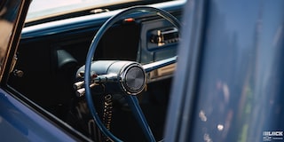 A Shot of the Steering Wheel of a 1967 Blue Chevy C10 Truck Viewed from outside the Left Window