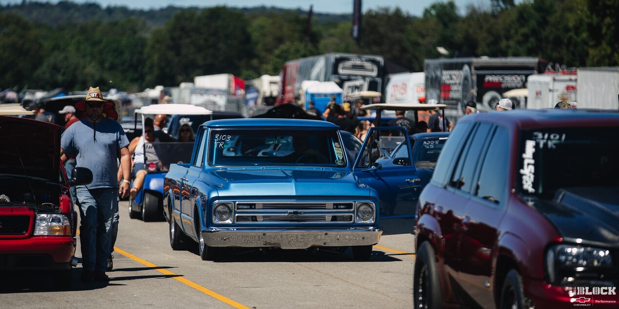 Three Quarters View of a Blue 1967 Chevy C10 Truck Lining Up for a Racing Event along with Other Cars on a Sunny Day