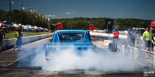Rear View of a Blue Chevy C10 Truck Gearing Up for a Racing Event with Smoke Coming the Rear as It Burns Rubber