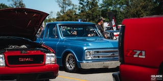 Three Quarters View of a Blue 1967 Chevy C10 Truck Lining up for a Racing Event along with Other Cars on a Sunny Day