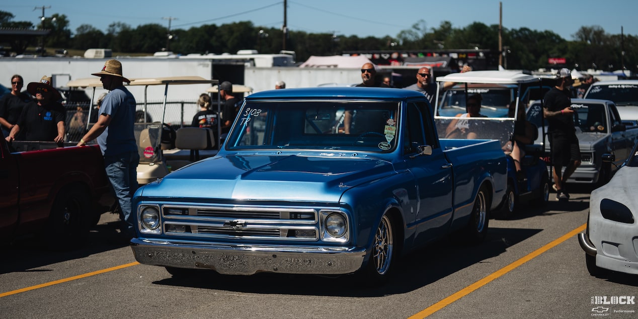 Three Quarters View of a Blue 1967 Chevy C10 Truck along with Other Cars at an Event on a Sunny Day