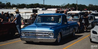 Three Quarters View of a Blue 1967 Chevy C10 Truck along with Other Cars at an Event on a Sunny Day