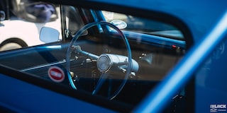 A Shot of the Steering Wheel of a Blue 1967 Chevy C10 Truck Seen from outside the Rear Window