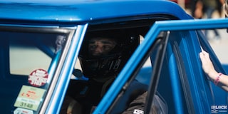 A Driver Wearing a Helmet Inside a Blue Chevy C10 Truck