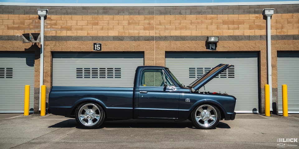Side View of a Black Chevy C10 Truck Next to a Professional Garage